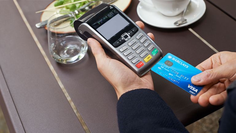 A Barclays Visa Debit card being inserted into a card reader at a restaurant